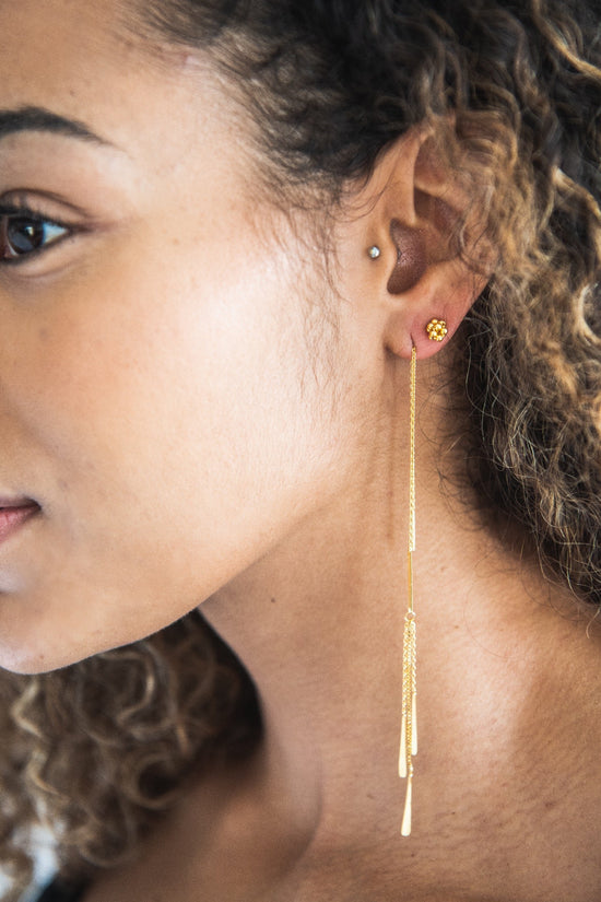 Close up of woman wearing Aretha Long Gold Feathered Threader Earring