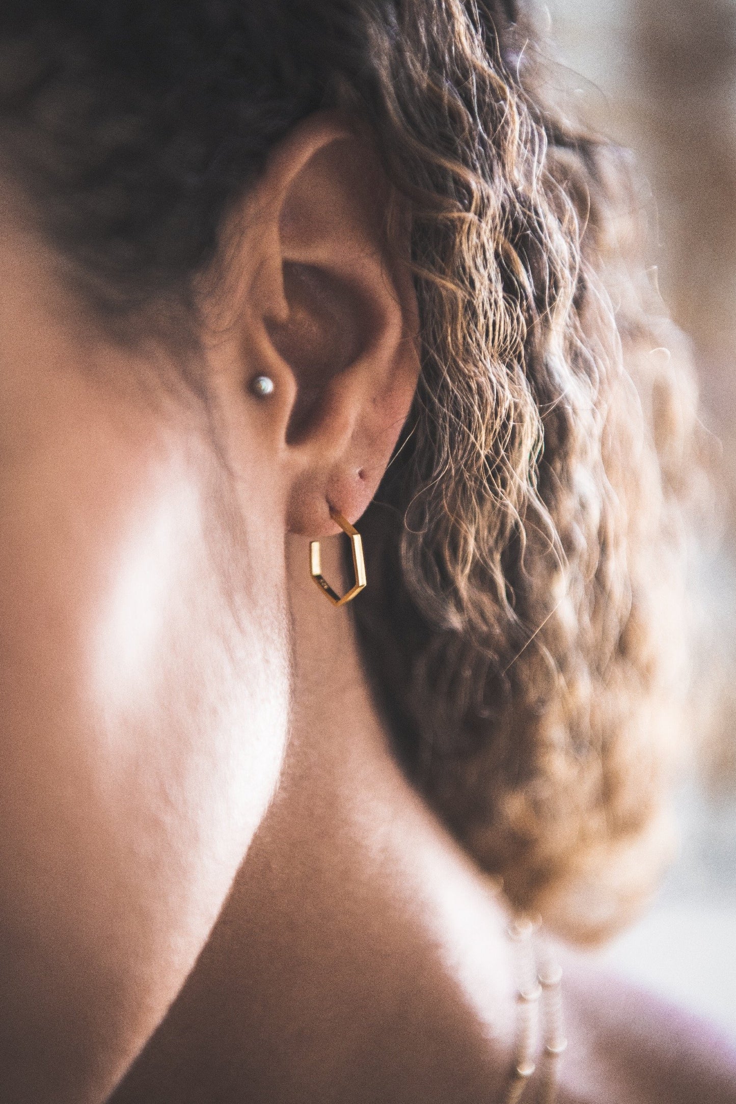 Close up of woman wearing Hexagon Hoop Stud earring