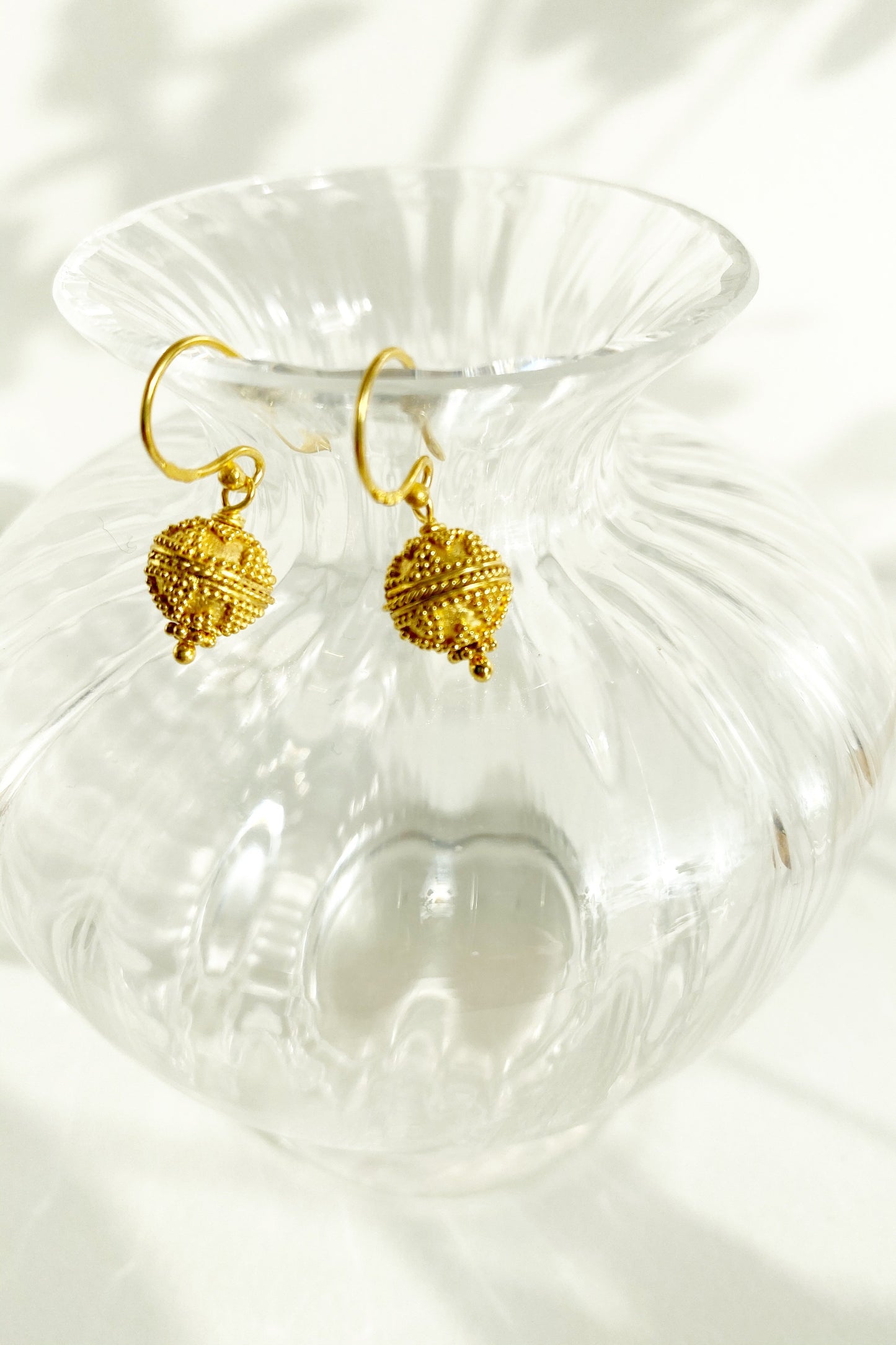 Triangle Dot Harmony Ball Earrings hanging over rim of glass vase