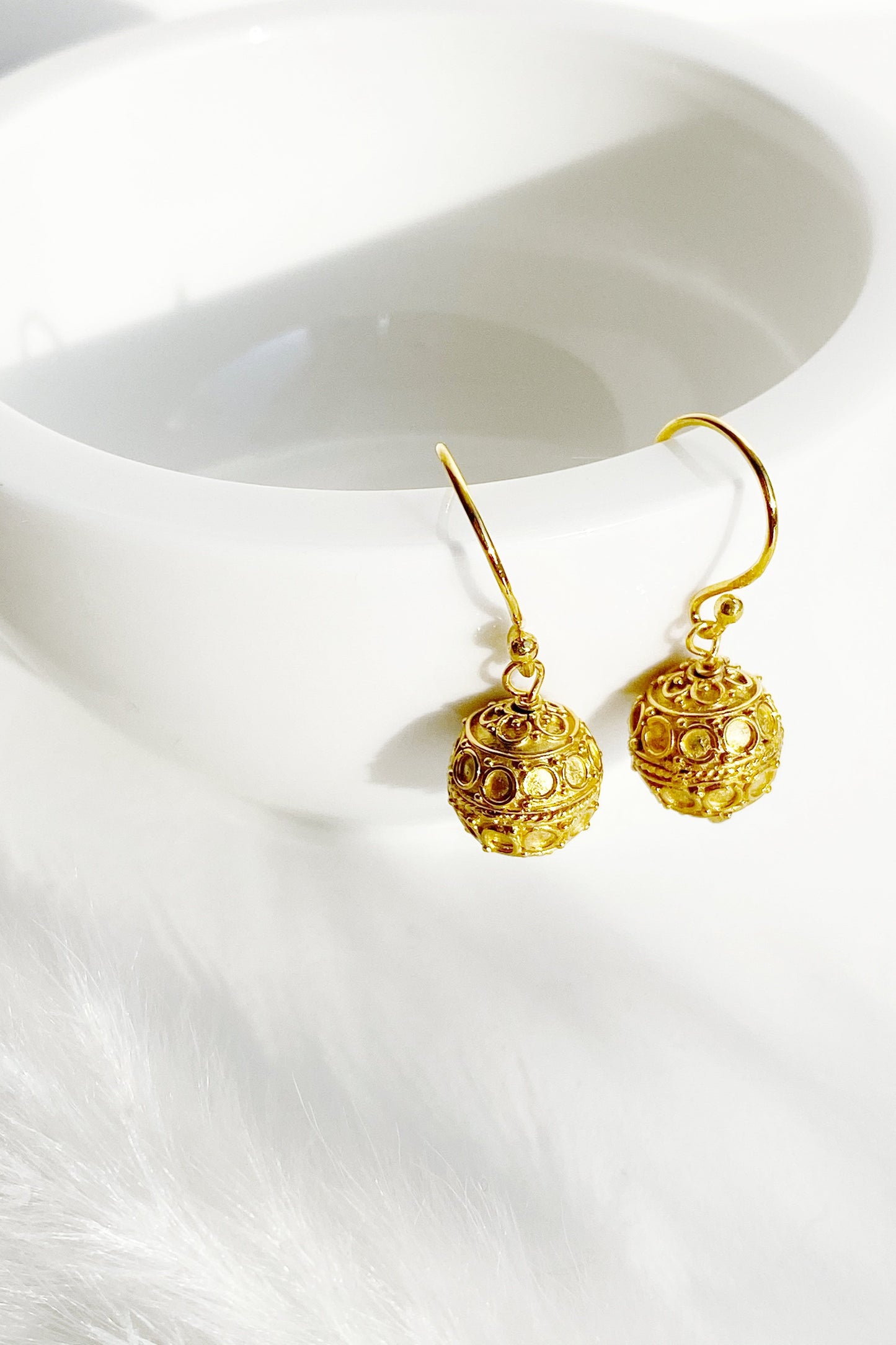 Circle Design Harmony Ball Earrings hanging from a rim