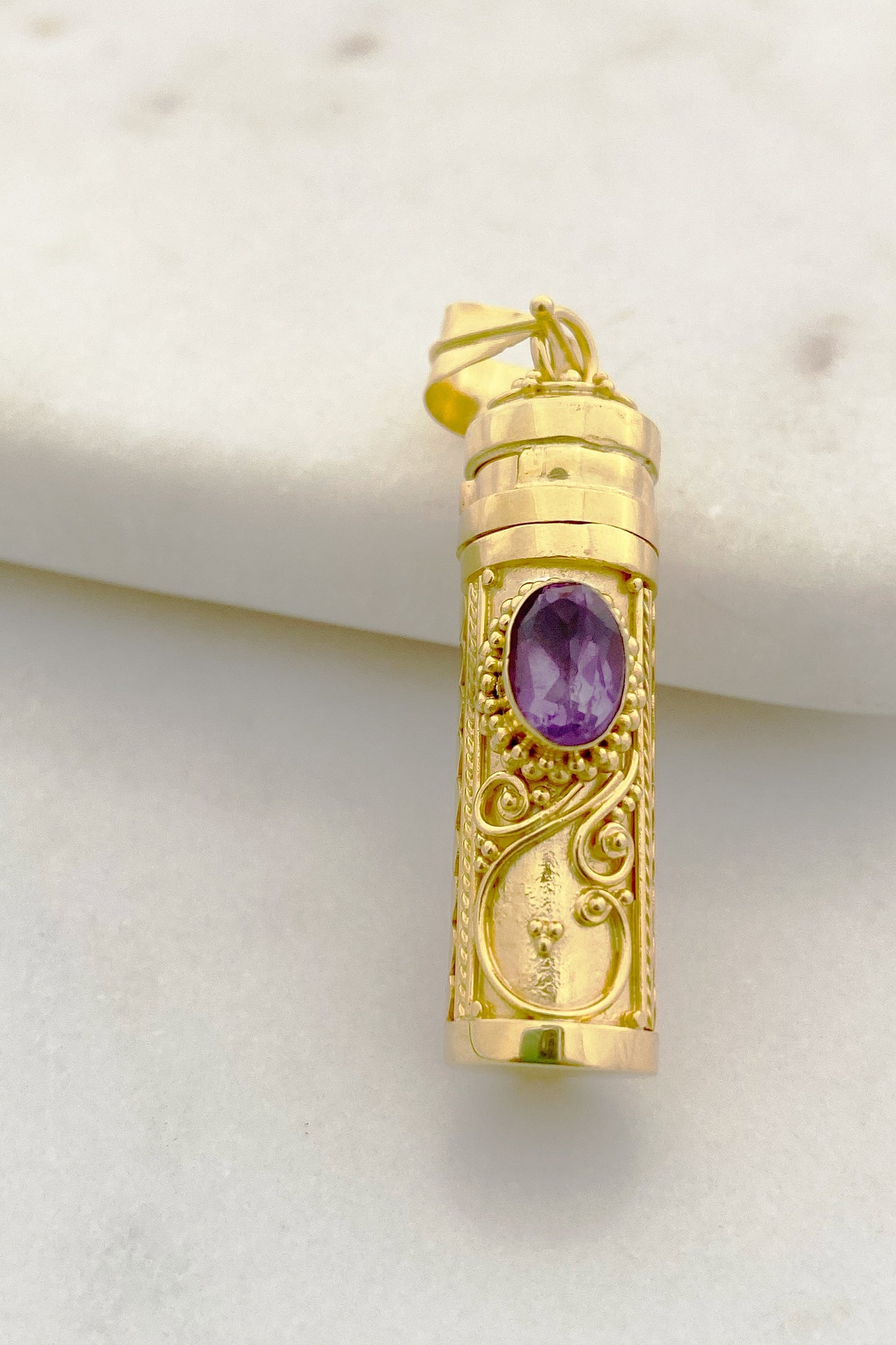 Chain-less Amethyst Wishing Locket on an uneven surface