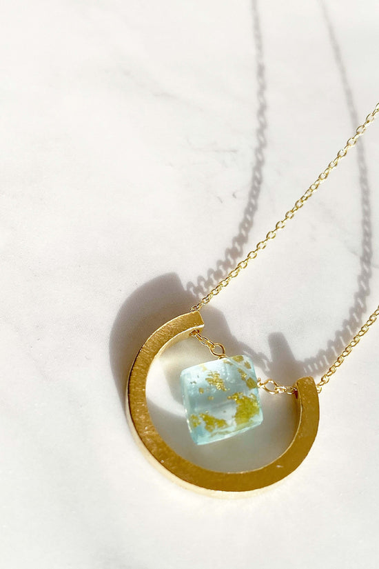 Close up of Guardian Luna Blue Topaz Necklace with light shining through it