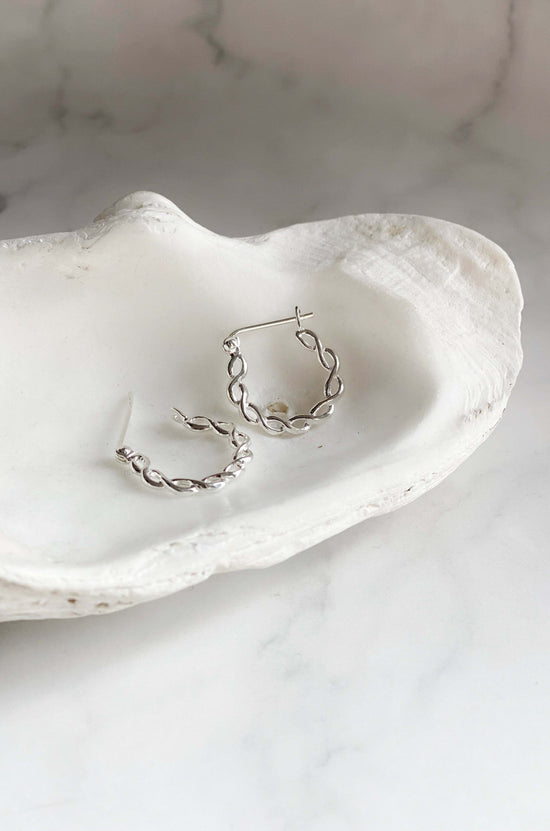 Close up of silver Twisted Hoops in white dish